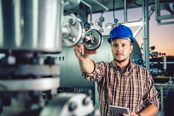 Worker at the measuring device, helmet, blue